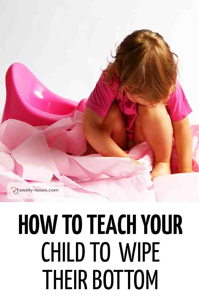 A little girl sitting next to a potty, playing with some rolls of toilet paper (learning to wipe her bottom). #parenting #toddler #wipebottom #toilettraining #pottytraining #toiletingkid